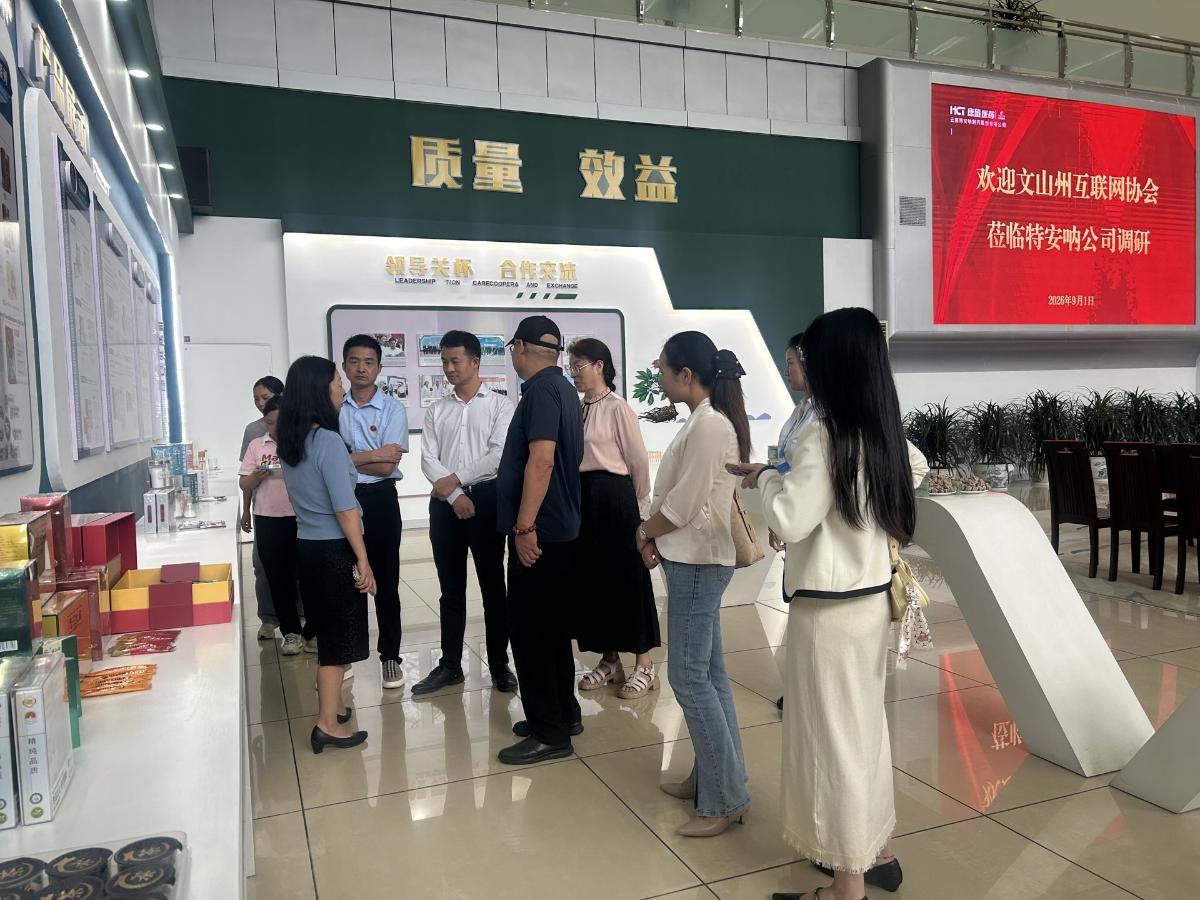 特安纳"质量 效益"标语墙前，协会代表与特安纳负责人交流